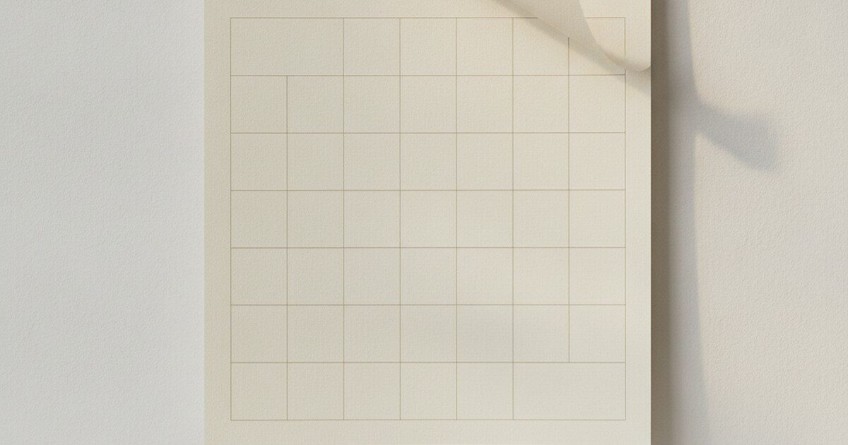 A wall calendar page caught mid-turn in soft window light